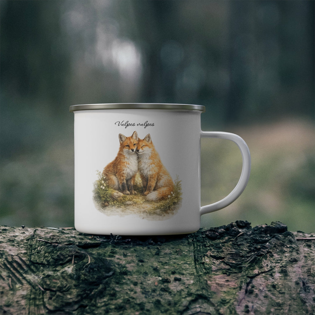 Hippuli brändin valkoinen emalimuki, jossa on maalattu kuva kahdesta toisiinsa nojaavasta Vulpes vulpes -ketusta luonnon keskellä. Kuva luonnossa.