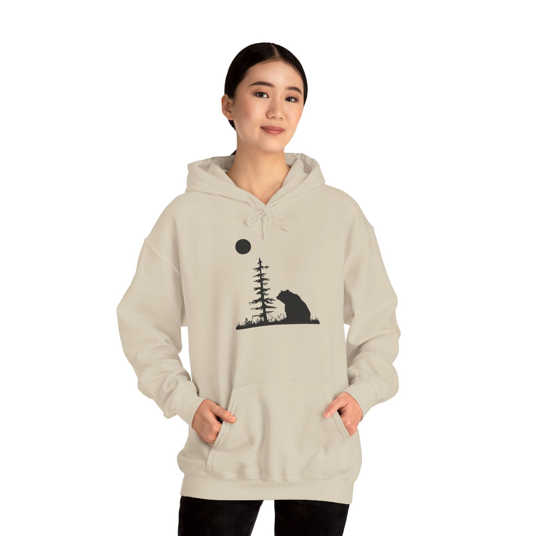 Beige unisex huppari jossa karhu istuu ja katselee kuutamoa puun vieressä. Kuvassa paita naisen päällä.