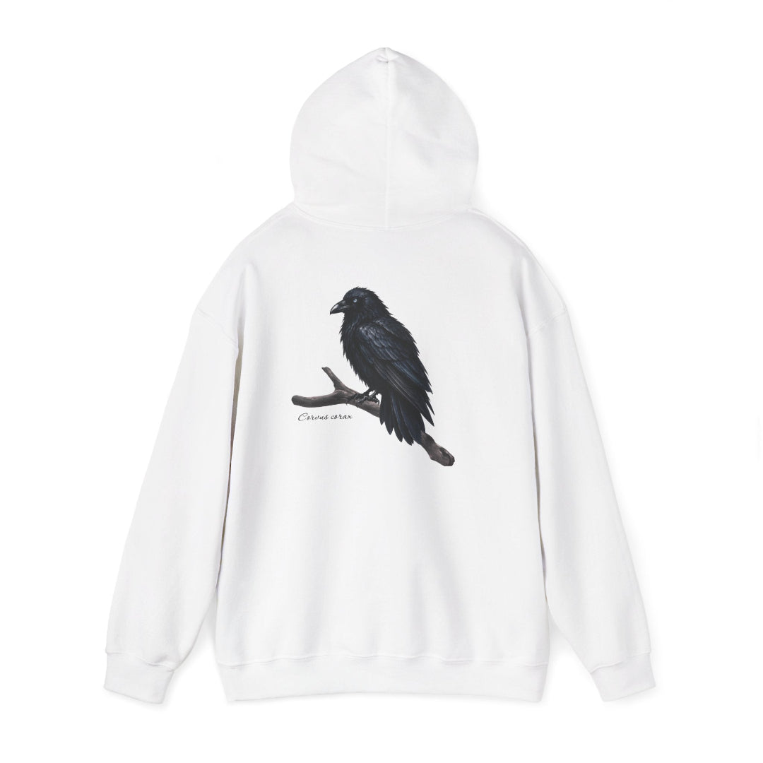 Hippuli brändin valkoinen huppari, jossa on maalattu kuva puun oksalla istuvasta Corvus corax -korpista. Kuvassa huppu ylhäällä.