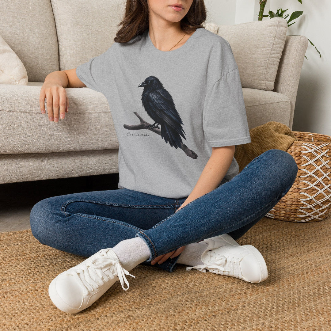 Hippuli brändin harmaa unisex puuvillainen t-paita, jossa on maalattu kuva puun oksalla istuvasta Corvus corax -korpista. Kuvassa naisen päällä.